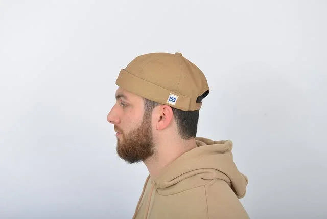 Man wearing a brown beanie and hoodie against a white background